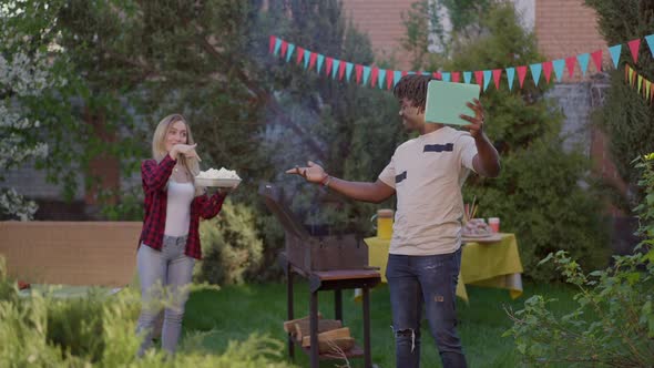 Wide Shot of Happy Young African American Man Using Video Chat on Tablet Bragging Family Picnic