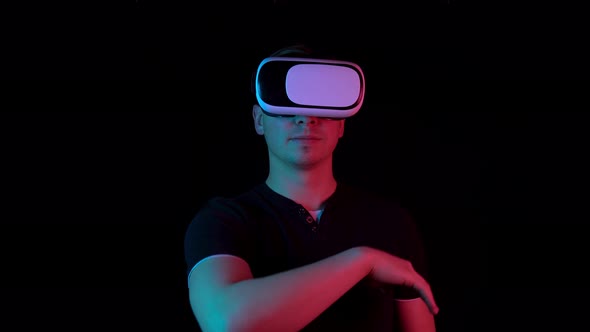 Young Man in VR Glasses. A Man Immersed in Virtual Reality Makes Movements with His Hands