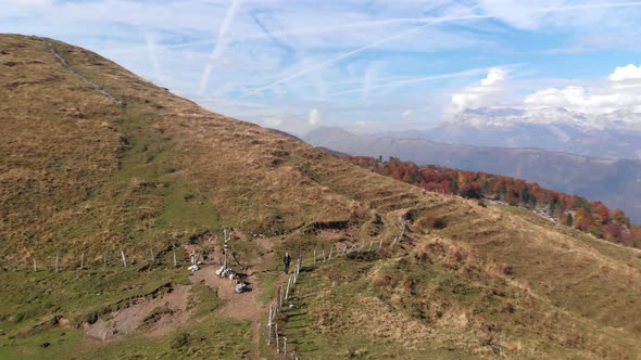 Aerial shot of blonde female hiking a mountain ridge.