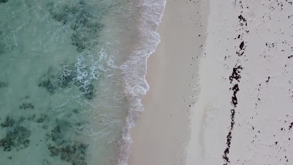 Aerial drone looking straight down on crystal clear tropical Caribbean sea crashing on a white sand