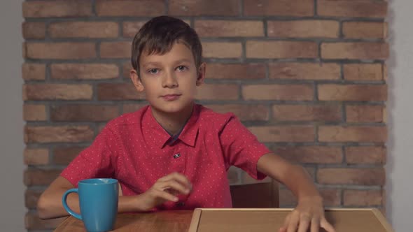 Child Sitting at the Desk Holding Flipchart with Lettering Coffee on the Background Red Brick Wall.