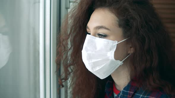 Beautiful Lady in a Face Mask Is Looking Into the Window