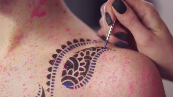 Master Painting Pattern on the Girl's Body Using Brush and Different Colors