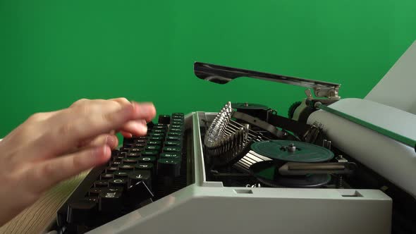 The girl is typing on a retro typewriter on a green background. Chromakey.