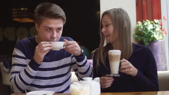 Young Smiling Couple in Outdoor Coffee Shop Smiling and Drinking Coffee