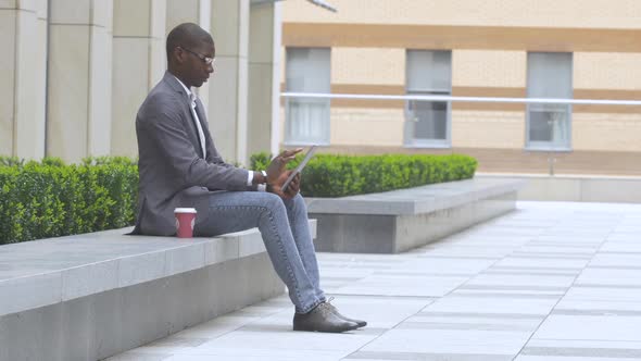 Businessman Working on Laptop Outdoors on a Background of Corporate Building