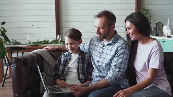 Son and parents sitting at home, having video call on laptop