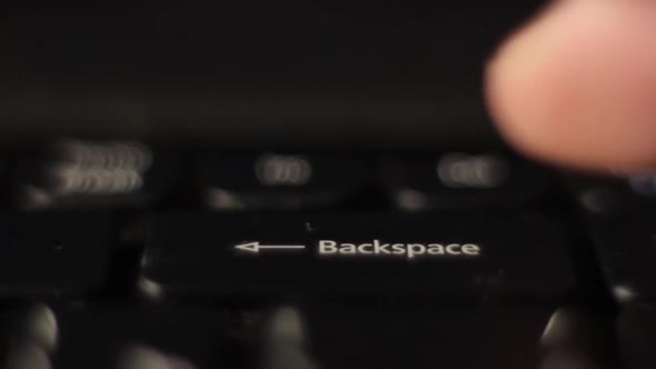 The Finger Presses the Backspace Button on the Keyboard. Close-up.