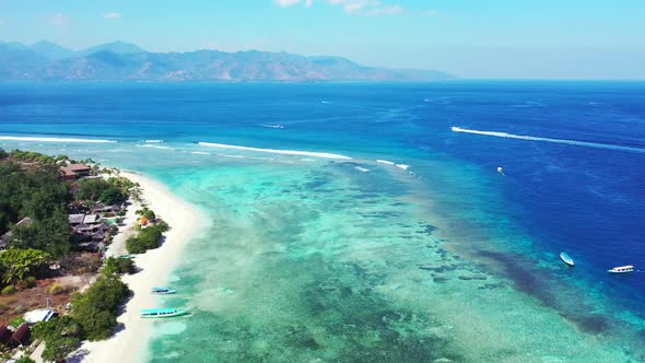 Aerial above travel of idyllic lagoon beach break by clear water with white sandy background of a pi