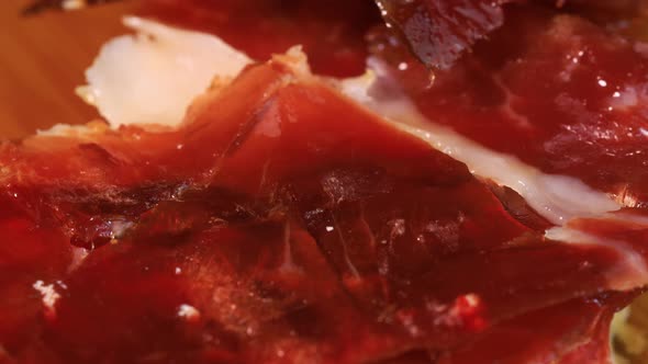 High quality spanish serrano ham with bread rotating on wooden board, close up view from above. Trad