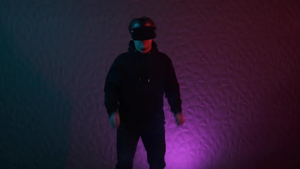 Man in Black Hoodie and VR Helmet on His Head Dances in Neon Purple Red