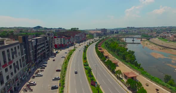 Model road and city with buildings and river, drone view, bridge on the river, cars running on the r