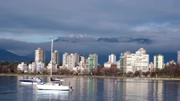 Little boat going across the frame with two other boats anchored off English Bay close to downtown V