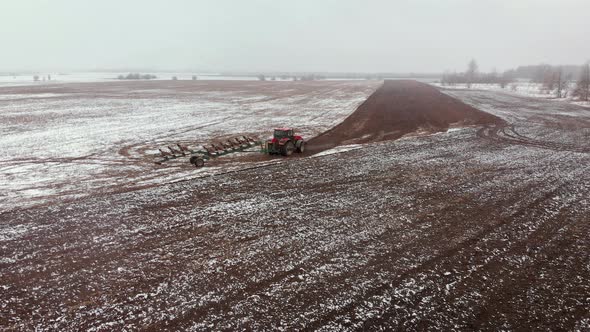 Aerial Tractor with a Plow Near a Furrow in a Snowcovered Field