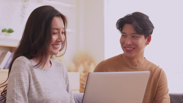 At home in the living roomm.Asian couple enjoy talking conversation together on sofa with happiness