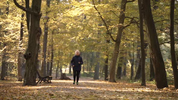 Active Elderly Woman Jogging in Autumn Park