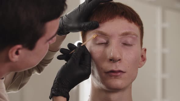 A Man Eyebrow Master Waxing the Hairs of the Eyebrow of His Male Client