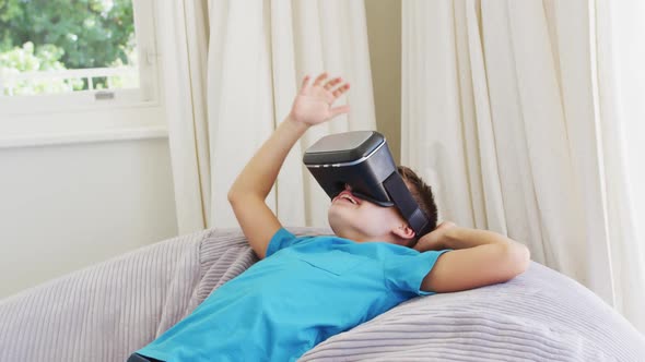 Caucasian boy wearing vr headset while lying on the bean bag at home