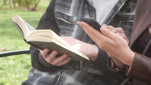 Beautiful Couple Sitting On A Bench In The Park In The Spring And Reading A Book