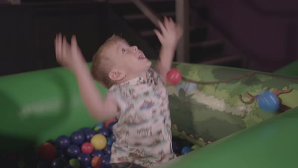 Young Boy Playing in Ball Pit, Smiling and Throwing the Balls Around. - Ungraded
