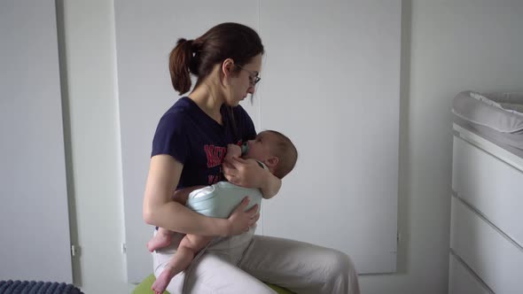 A Young Mother Rocks Her Baby on a Fitness Ball