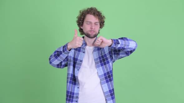 Confused Young Bearded Hipster Man Choosing Between Thumbs Up and Thumbs Down