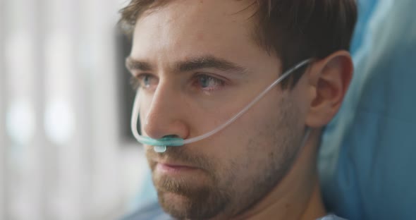 Upset Man Lying with Oxygen Nasal Catheter on Face Preparing for Surgery