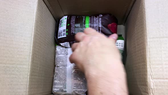 A Man Collects a Box of Humanitarian Aid for the Needy Rice Cereals Canned Goods in Tins