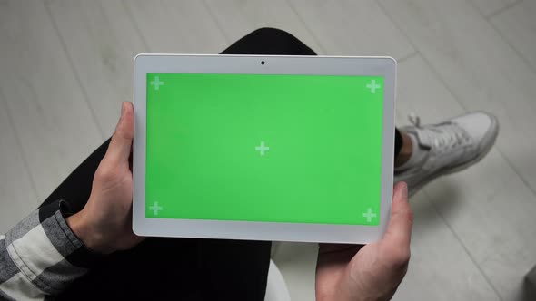 Man Sitting on Chair Looking at Digital Tablet with Green Screen Chroma Key