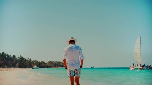 Man Walking On Tropical Beach.Guy Relaxing On Caribbean Beach.Man In Hat Healthy Skin Sunbathing