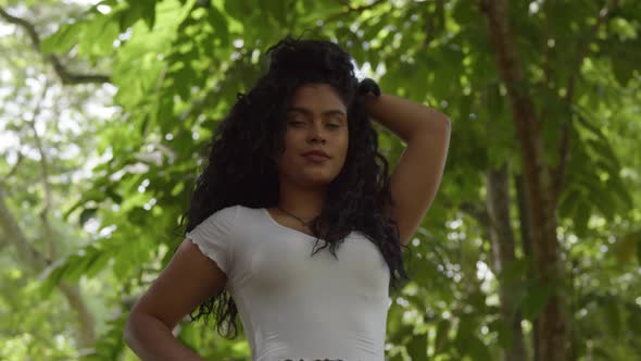 Low angle shot of a curly hair model playing in her hair at the park