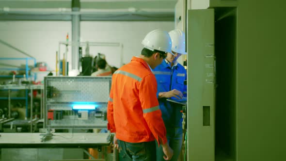 two asian coworker brainstorm  explaining and solves the process of the cnc operate machine