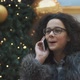 Happy Young Girl Talking on the Phone on the Background of the Christmas Tree - VideoHive Item for Sale
