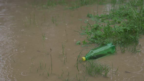 An Empty Plastic Bottle of Carbonated Drinks Floats on the Water During a Flood. Very Dirty Water