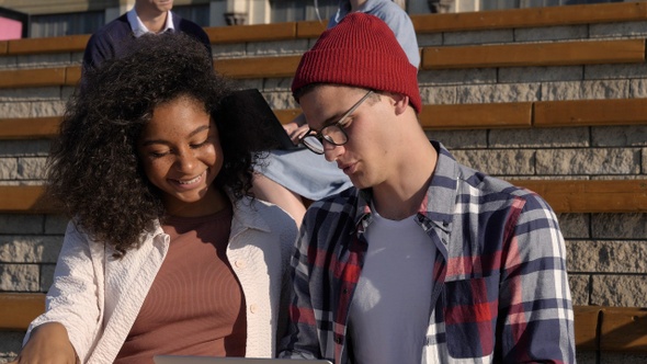 Mixed race students couple spending time together doing