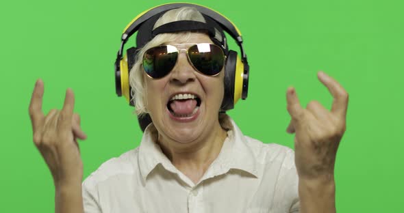 Elderly Woman Listens To Music in Headphones and Dances. Grandmother. Chroma Key