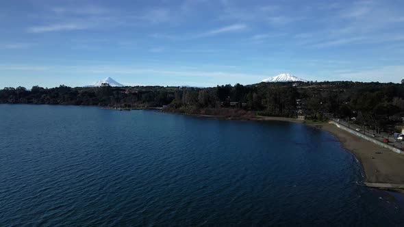 Aerial view dolly out playa hermosa of puerto varas, Llanquihue lake, calbuco and osorno volcanoes i