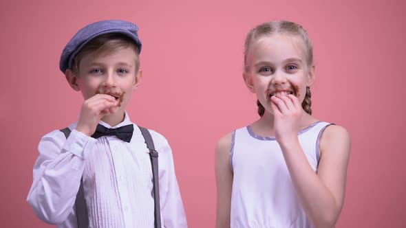 Cheerful Boy and Girl Smiling and Eating Chocolate Candies, Celebrating Holiday