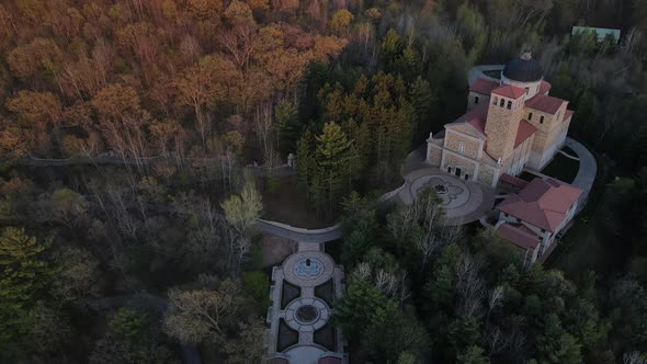 Panoramic view of church nestled into the forest on a mountain in autumn.
