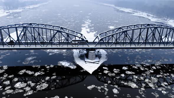 Snowy bridge over river with floe in winter