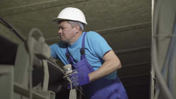 Confident Serious Man in Safety Helmet Checking Equipment at Factory. Confident Expert Controls