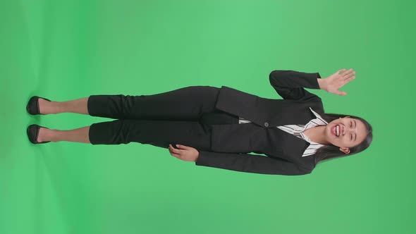 Full Body Of Asian Business Woman Waving Hand And Smiling While Standing On Green Screen