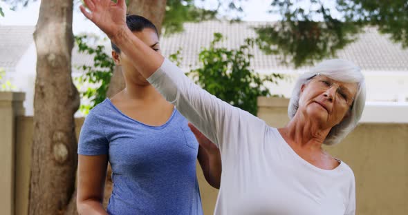 Trainer assisting senior woman in exercising 4k