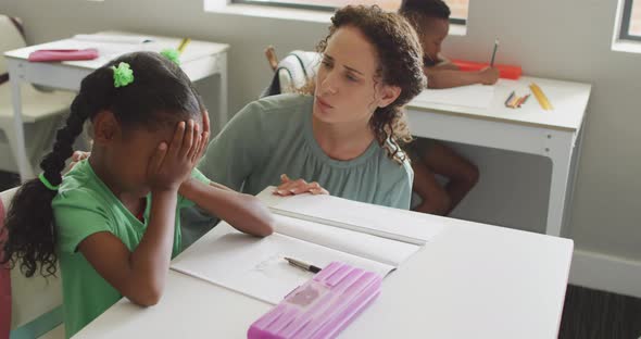 Video of caucasian female teacher supporting sad african american girl during lessons