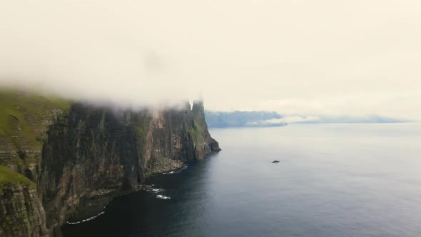 Drone Along Misty Coastline Cliffs Of Vagar With Trollkonufingur