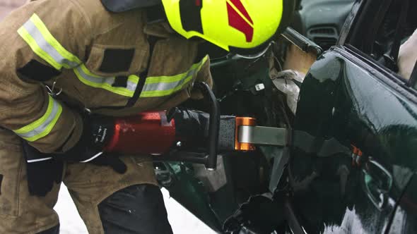 Firefighter Using Jaws of Life To Extricate Trapped Victim From the Car