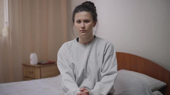 Portrait of Serious Young Caucasian Woman Sitting on Bed Disagree Gesturing Looking at Camera