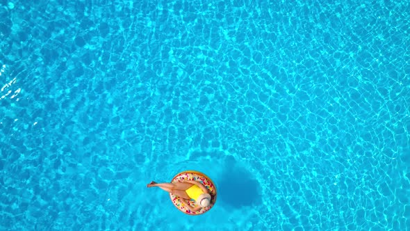 Aerial View of a Woman in Yellow Swimsuit Lying on a Donut in the Pool