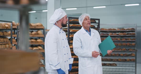 In a Bakery Factory Young Baker and Old Man