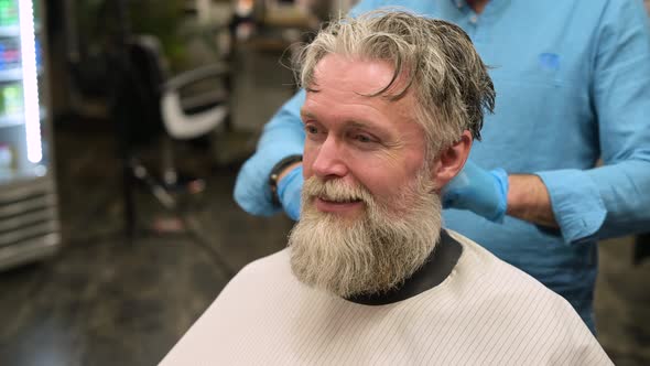 Overgrown gray-haired man waiting for a haircut in a barbershop